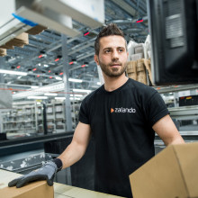 Logistics employee in black Zalando shirt handling boxes