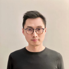 Portrait of Ray Cao in a black long sleeve and dark-rimmed glasses