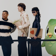 Three people with a baby stroller are waiting behind a barrier with the duolingo owl