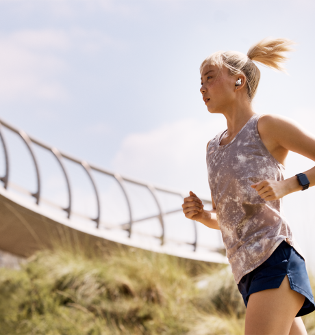 Woman running outdoors, wearing a smartwatch an ear pods
