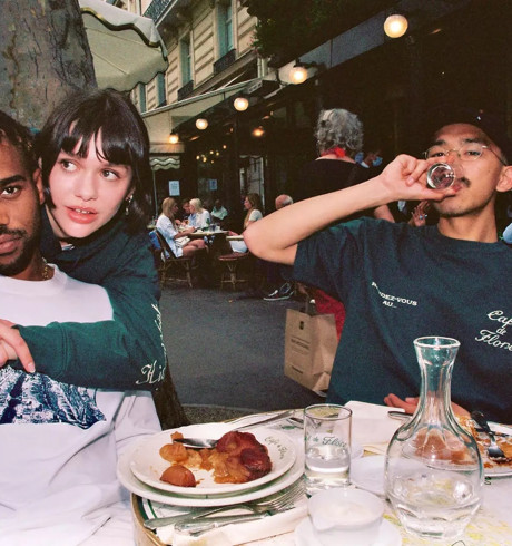 Three young people at a busy sidewalk cafe table with a half eaten meal in front of them