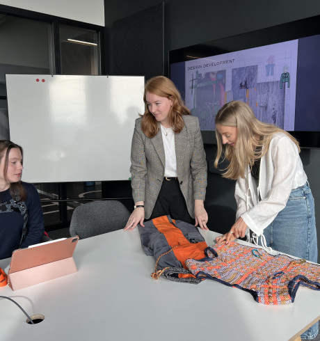 Two young female students present their prototype to a GFF representative