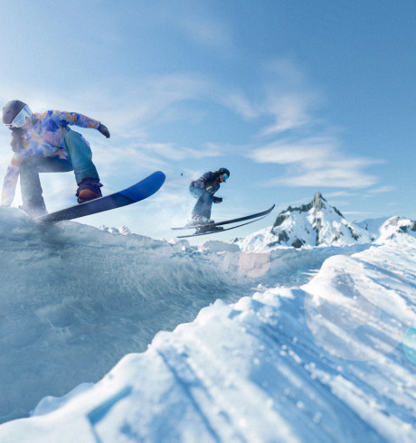 two snowboarders in action jumping over icy mountain ridges