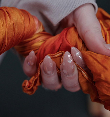 a twisted strand of orange silk held in hand