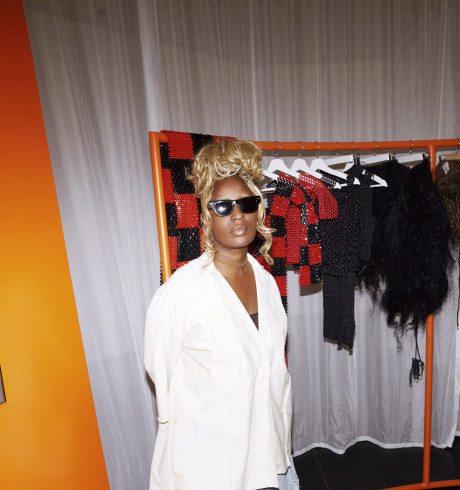IAMISIGO posing in front of an orange clothes rack