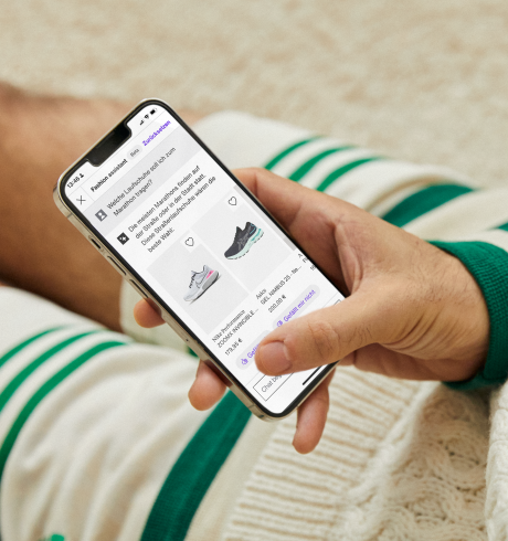 Auf dem Boden sitzende Person, die auf dem Smartphone den Zalando Fashion Assistant nutzt; nur Hand und Beine sind zu sehen