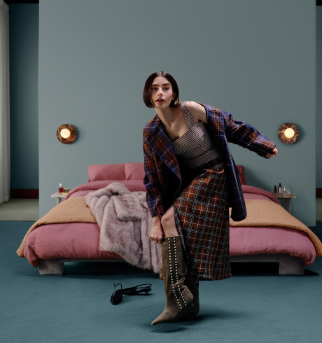 Lily Collins standing awkwardly on one leg while putting on shoes in a bedroom scenario