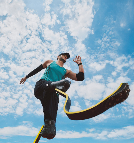 shot from below: male runner with two prosthetic legs mid-sprint