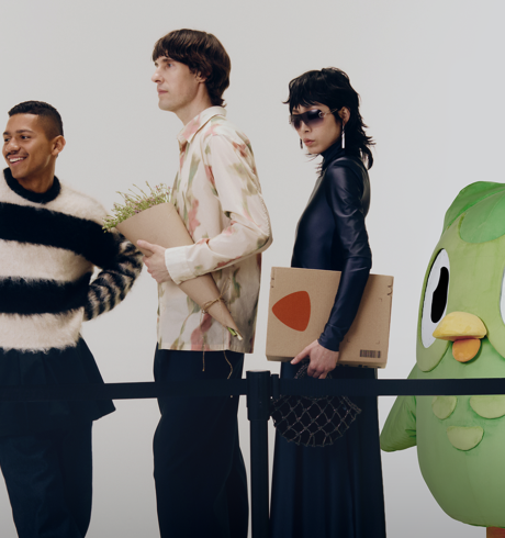 Three people with a baby stroller are waiting behind a barrier with the duolingo owl