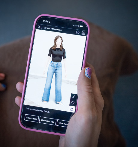 A hand with colourful nails holding a phone, showing the Zalando virtual fitting room