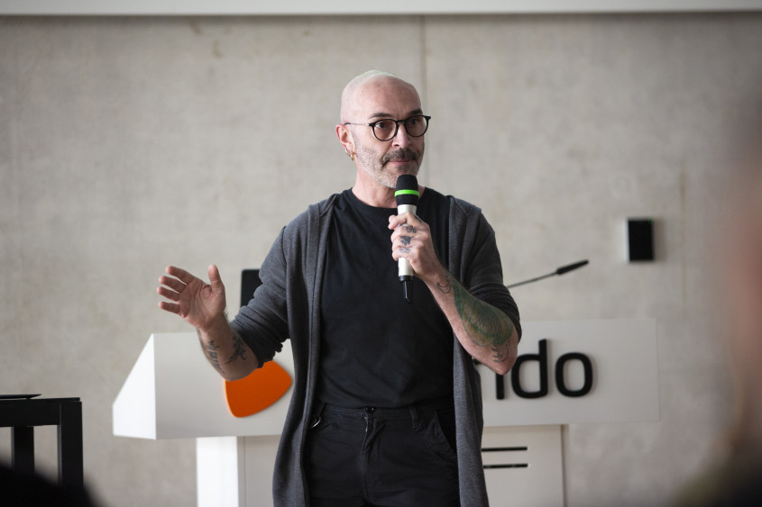 Michele Pazzini stands in an auditorium with a microphone in hands