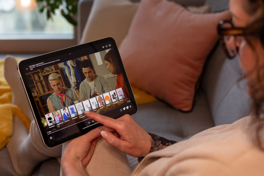 Customer with tablet: on screen GZSZ ist playing, underneath fashion items to chose from