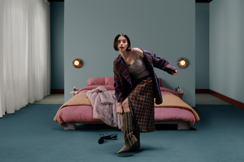 Lily Collins standing awkwardly on one leg while putting on shoes in a bedroom scenario