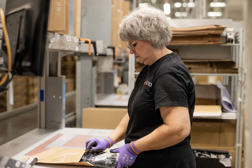 An employee at the pack station carefully places an item into a shipping bag
