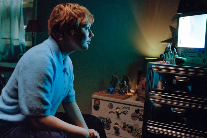 Woman in a dark room looking at a bright screen