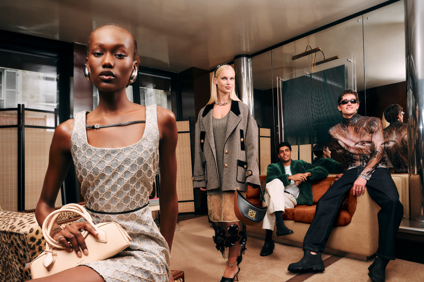 A group of young people in trendy outfits; the two men loungin on the sofa, one of the women perched on an armchair