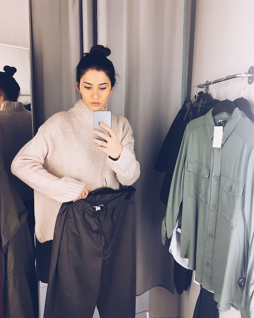 Woman trying on new clothes in front of the mirror in a fitting room