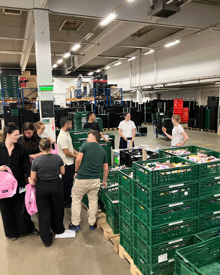 A group of volunteers standing around crates with food items in a warehouse