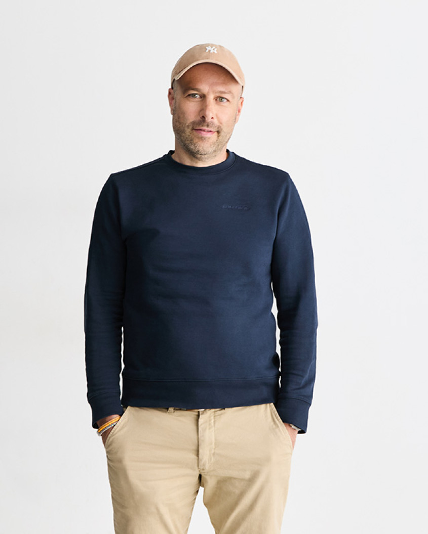 Portrait von Matthias Haase in einem navy Sweater, hellen Chinos und einem Cap