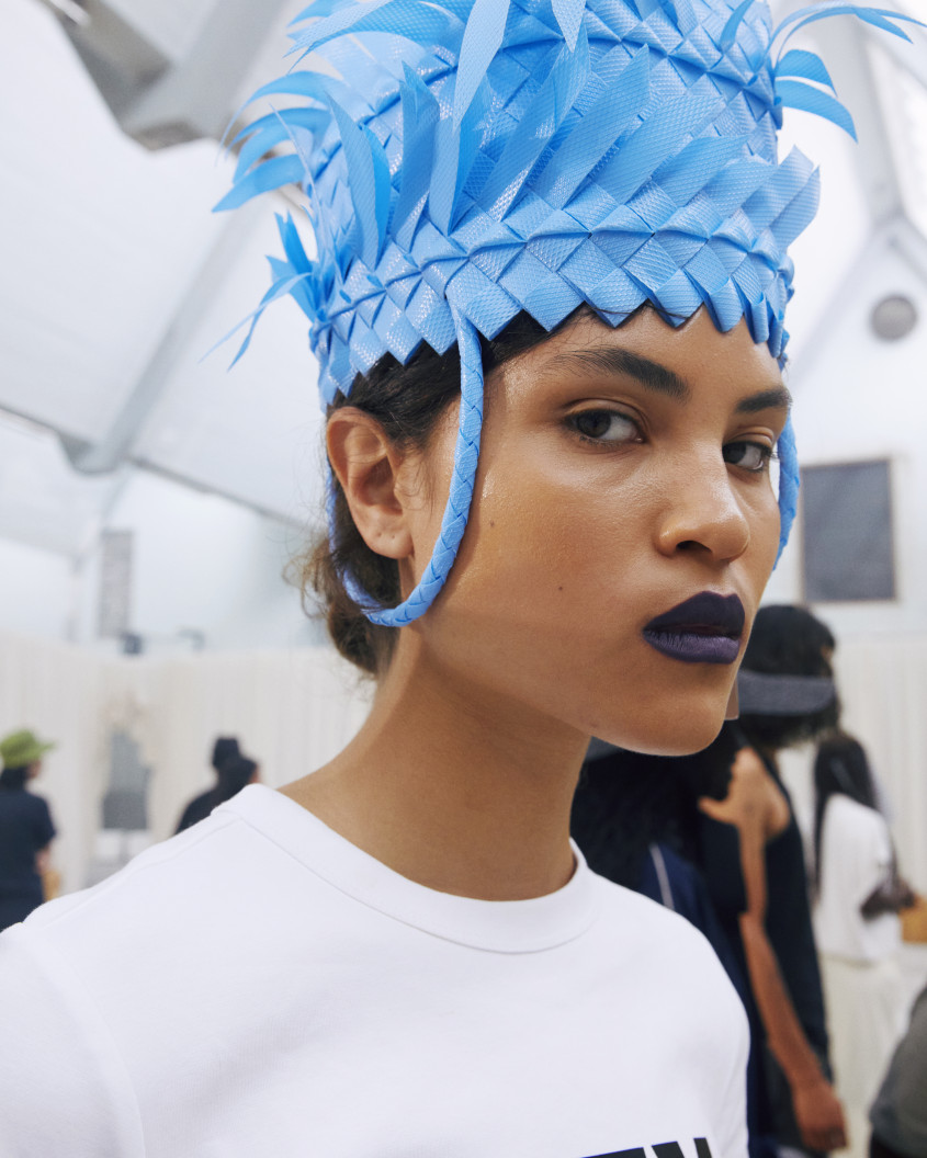 Fashion model backstage wearing an extravagant blue hat