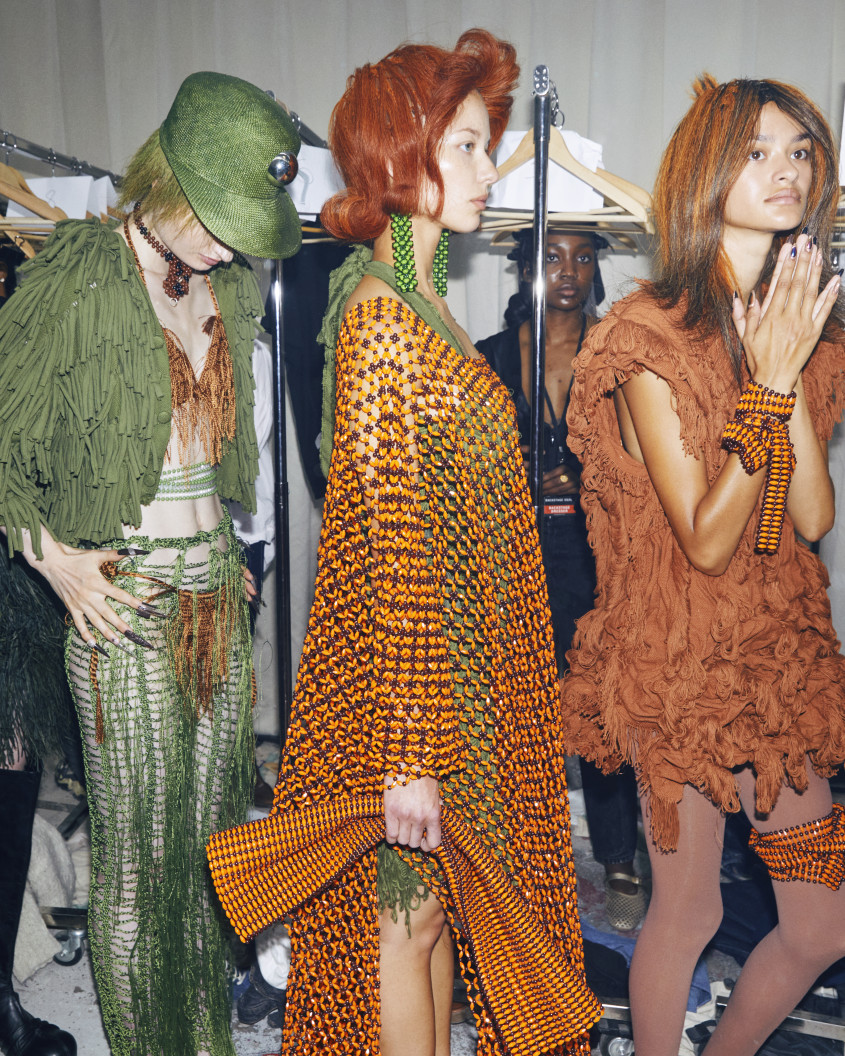 four fashion models standing in line backstage waiting their turn