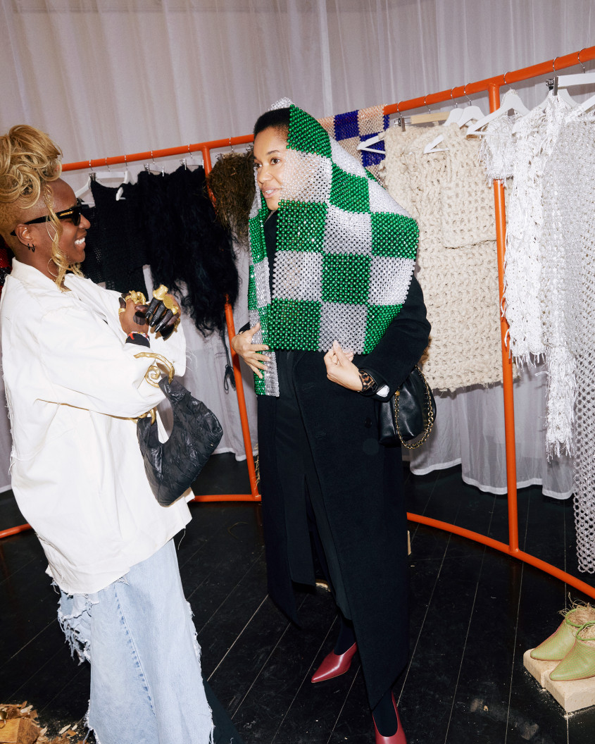 IAMISIGO smiling in conversation with another woman in front of an orange clothes rack