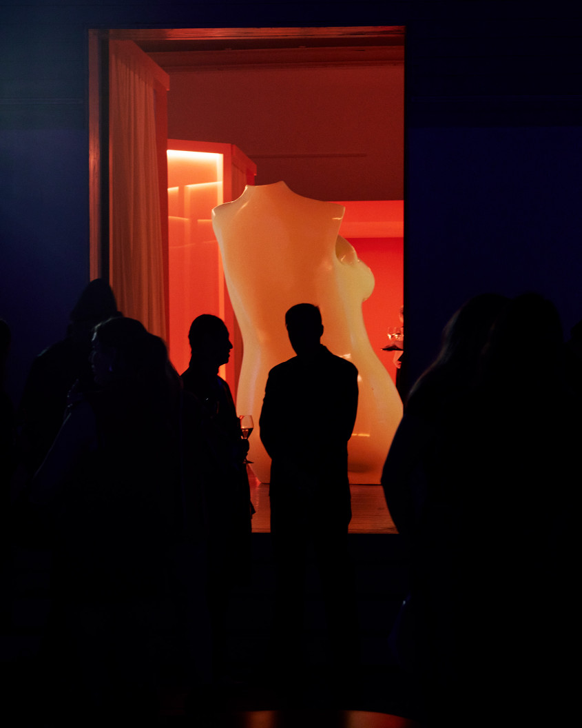 guests looking at a larger than life statue of a female naked torso