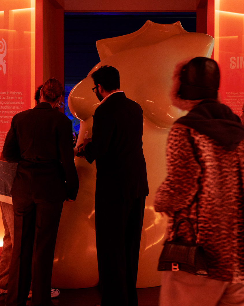 guests looking at a larger than life statue of a female naked torso