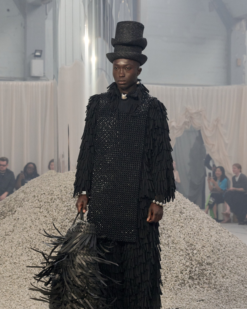 Fashion model dressed all in black with a big black feather bag