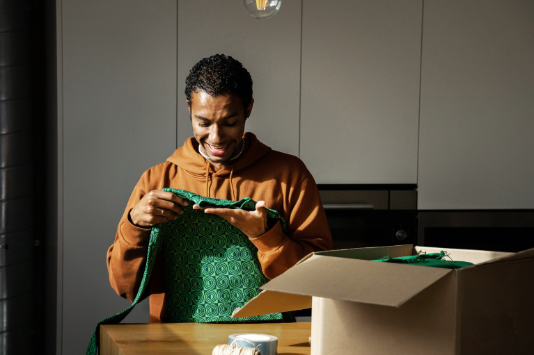 Man looking at green fabric next to an open cardboard box