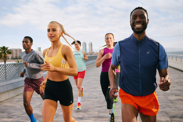 Five runners running over an urban bridge seemingly enjoying themselves