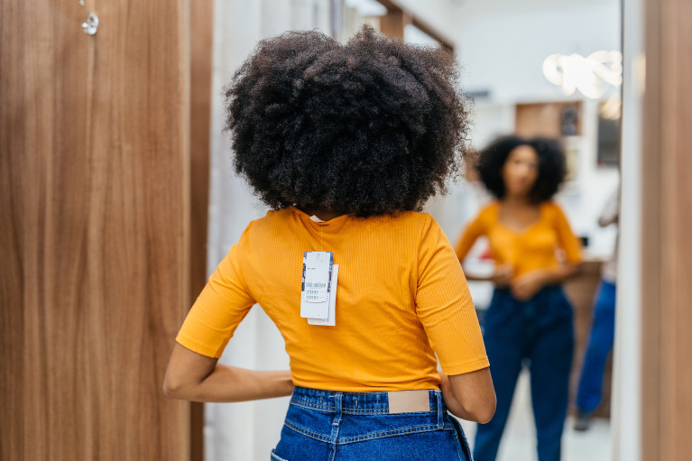 Woman trying on new clothes in front of the mirror in a fitting room