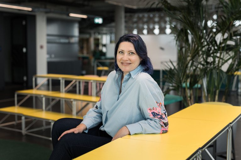 Galina Charni sitting at a yellow table smiling at the camera