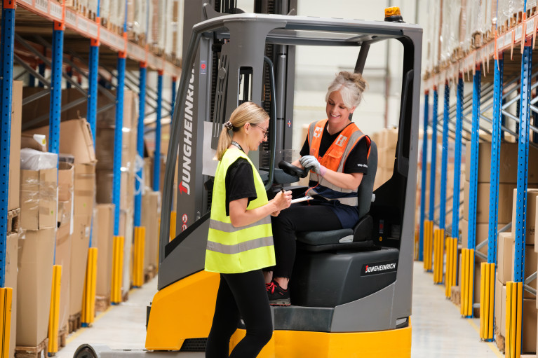 Two female logistics workers in a warehouse setting