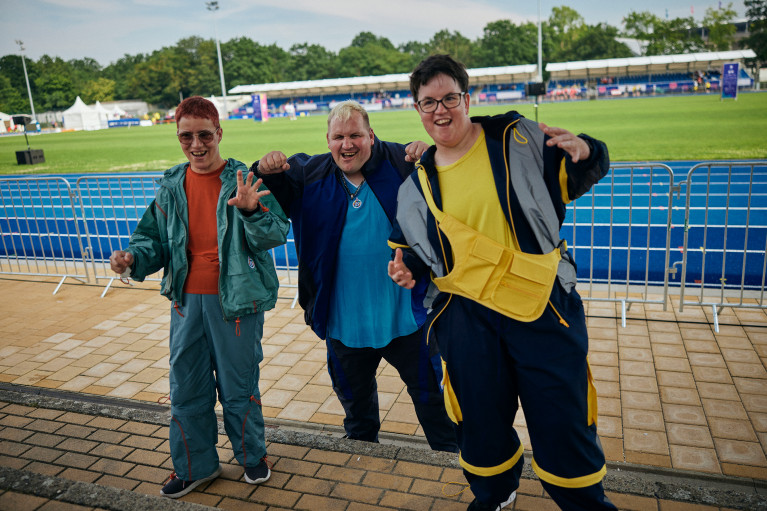 Three athletes presenting sports fashion to the camera; inside a stadium