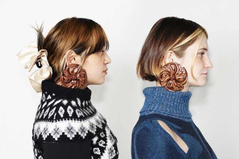 Headshot of two fashion models, both wearing warm jumpers and the same large distinctive earrings