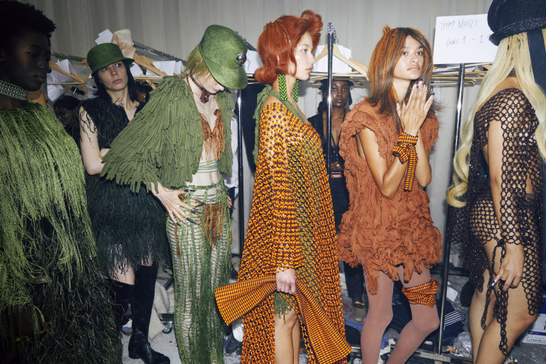 four fashion models standing in line backstage waiting their turn