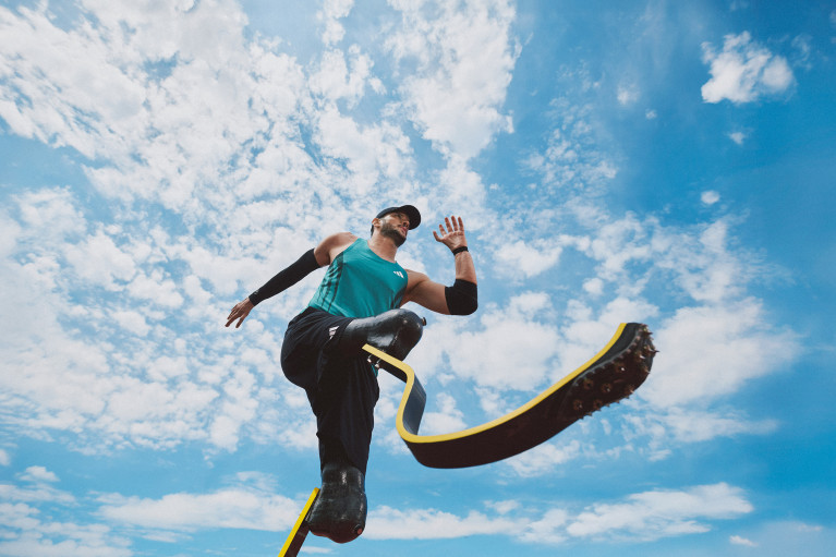 shot from below: male runner with two prosthetic legs mid-sprint