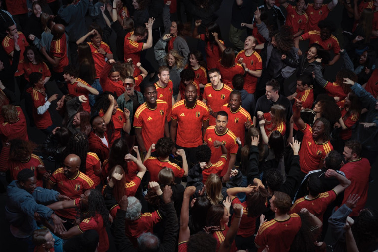 Five RBFA players standing in a celebrating crowd; only these five are looking up into the camera