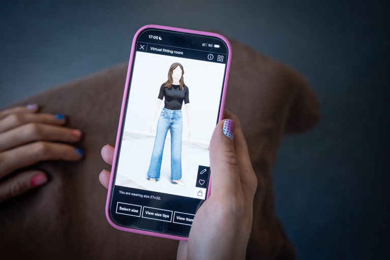 A hand with colourful nails holding a phone, showing the Zalando virtual fitting room